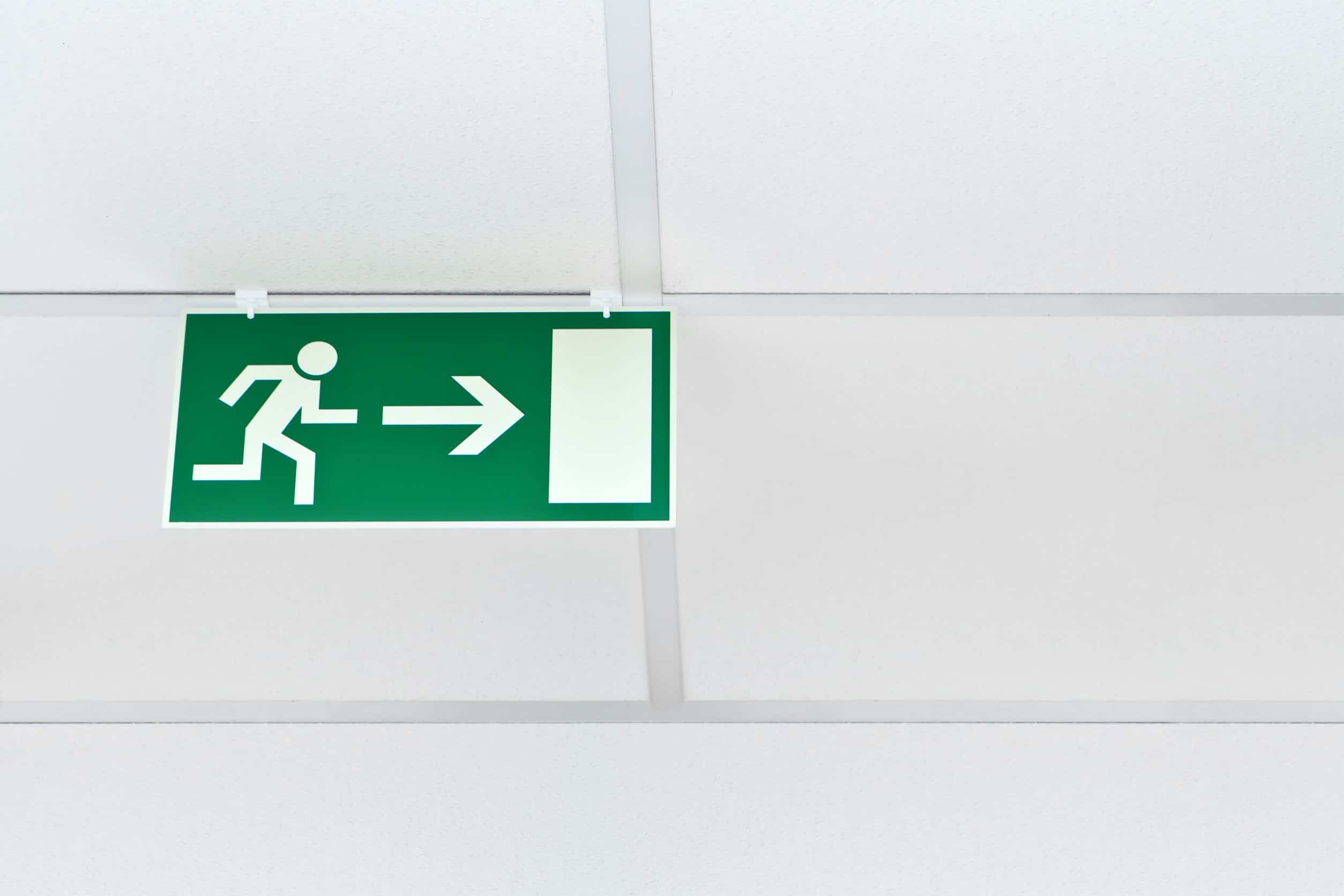 15899130 green emergency exit sign on a white wall